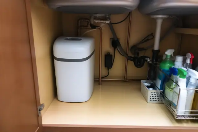 Water softener unit with copper plumbing installed under a kitchen sink in a Gilbert, AZ home.