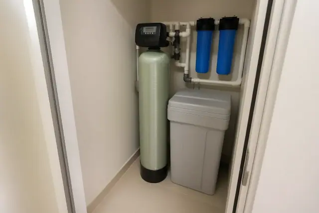 Water softener installation with white pipes and blue filters in a utility closet in Scottsdale, AZ.