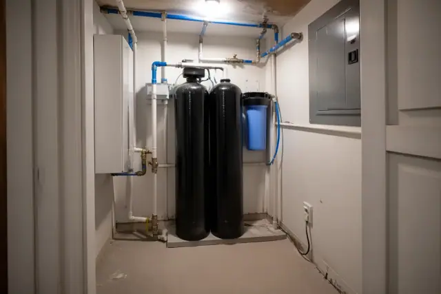 Carbon water filter tanks with blue and white PEX piping installed in an apartment utility closet in Tempe, AZ.