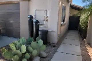 Whole house filtration system with PEX piping installed on a stucco wall at a home in Tempe, AZ.