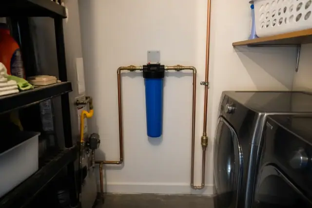 New blue whole house water filter installed with copper piping in a Tempe, AZ laundry room.