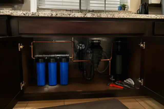 A whole house water filtration system with copper plumbing installed under a kitchen sink in a Tempe, AZ home.