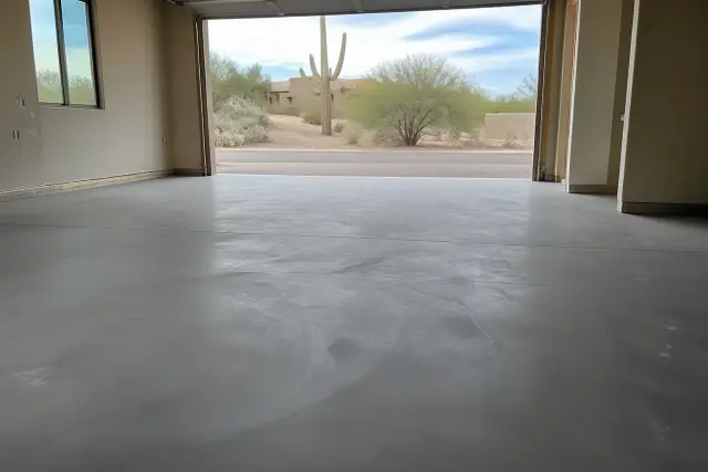 Concrete garage floor with matte topcoat prepped for recoating in Tucson, AZ with a view of saguaro cacti outside.