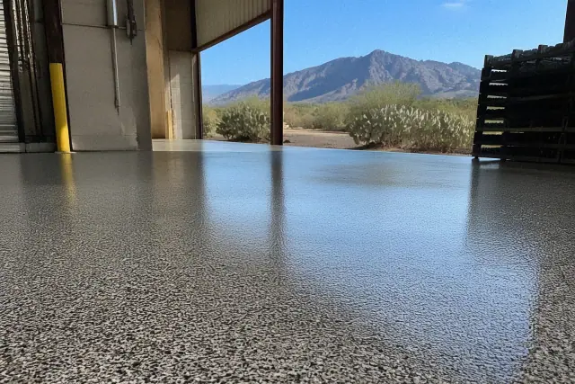 Finished flake epoxy flooring on an industrial concrete slab at a loading dock in Tucson, AZ, with desert mountain views.