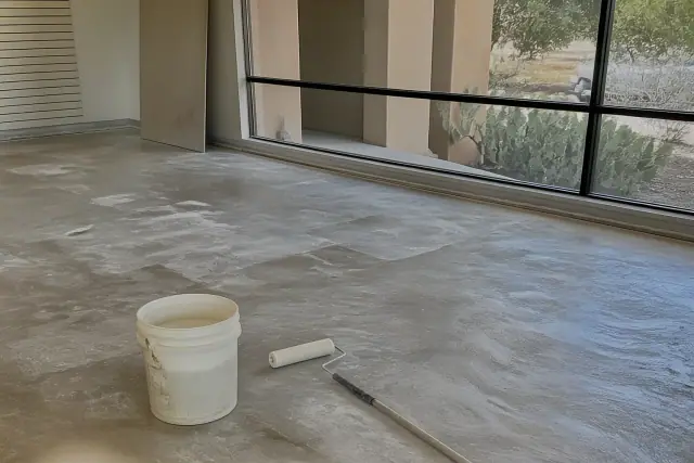 Sanded concrete retail floor prepared for epoxy installation with tools in a Tucson, AZ showroom.