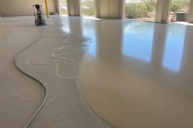 Industrial concrete floor with epoxy coating, sanding residue, and desert landscape in Tucson, AZ.