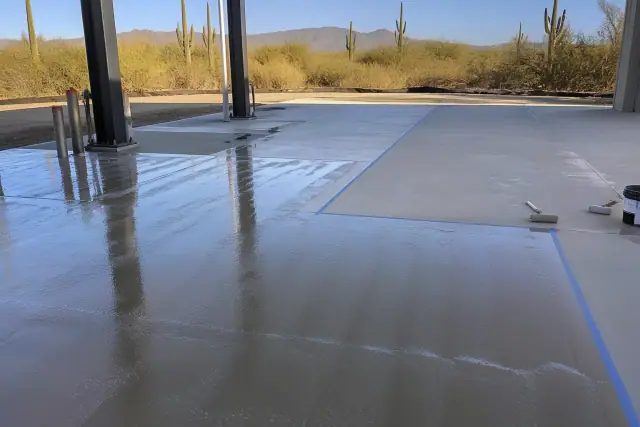 Commercial epoxy floor application on an industrial concrete slab with safety tape in Marana, AZ.