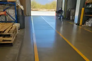Contractor cleaning a glossy industrial epoxy floor with marked lanes at a warehouse in Tucson, AZ.