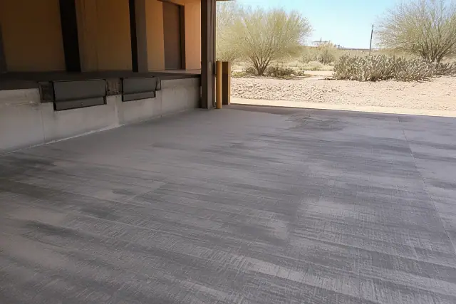 Concrete floor prepared for coating at a warehouse loading dock in Tucson, AZ with desert landscape in the background.