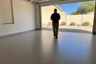 Technician inspecting a finished flake epoxy garage floor with desert landscaping visible in Tucson, AZ.