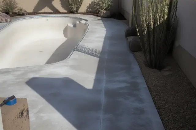Drained swimming pool with concrete deck surface in Tucson, AZ, ready for a protective sealant application.