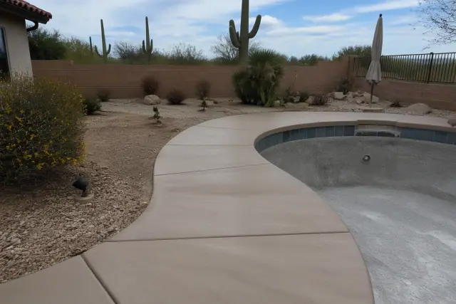 Concrete pool deck being prepped for sealant in Tucson, AZ with saguaro cacti in the background.