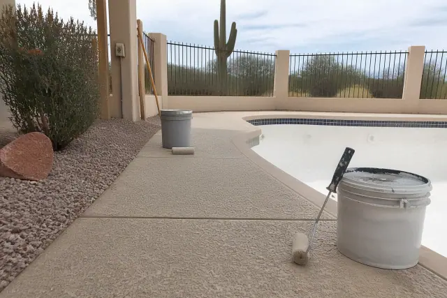 Epoxy coating application on a pool deck with paint rollers and buckets at a job site in Tucson, AZ.