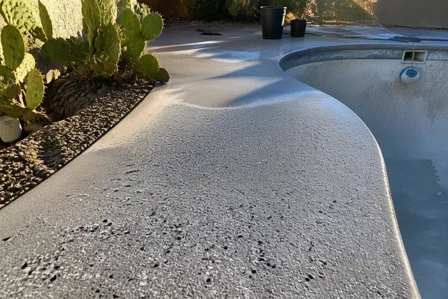 Flake and metallic pool deck coating being applied to a concrete walkway in Tucson, AZ, with surrounding prickly pear cacti.