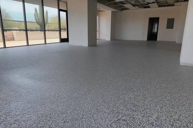 Commercial epoxy flooring with decorative flakes on a concrete floor in a Tucson, AZ shop with a cactus visible outside.