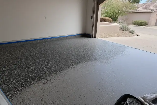 Concrete garage floor prepped with decorative flakes in an empty two-car residential garage in Casas Adobes, AZ.