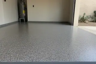 Close-up of a finished flake epoxy garage floor with prickly pear cacti visible through the open door in Tucson, AZ.
