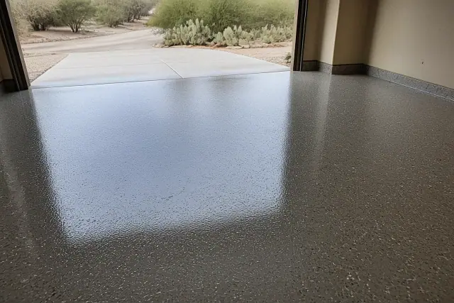 Freshly installed epoxy floor with decorative flakes in a residential garage in Tucson, AZ, with desert landscaping outside.