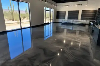 Glossy metallic epoxy floor reflecting overhead lights in a Tucson, AZ retail showroom with Saguaro cacti visible outside.