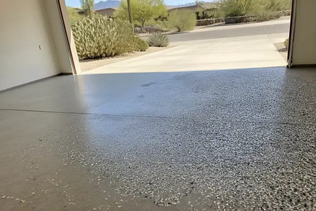 Partial-broadcast flake epoxy garage flooring in a Tucson, AZ residence with desert landscape in the background.