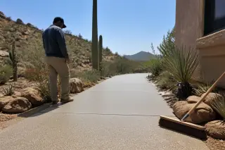Technician inspects a finished textured patio floor with Sonoran desert plants in Tucson, AZ.