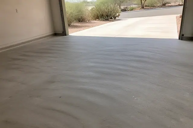 Empty two-car residential garage floor prepped for polyaspartic coating in Tucson, AZ, with desert landscape outside.