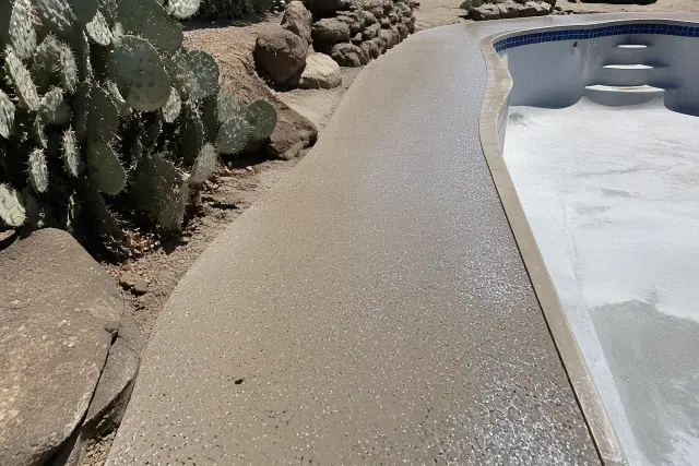 Polyaspartic pool deck coating being applied to a concrete walkway in Tucson, AZ, with visible vinyl flakes.