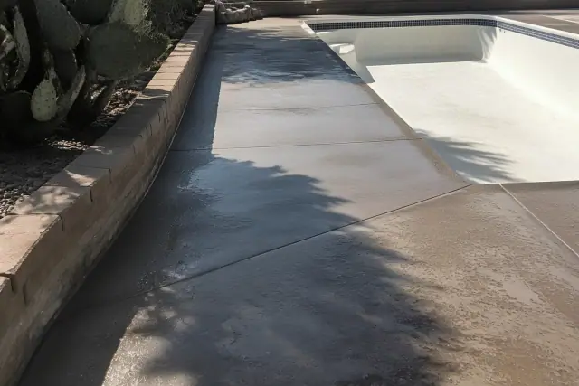 Moisture-wicking concrete pool deck coating being applied in Tucson, AZ, surrounded by prickly pear cacti.