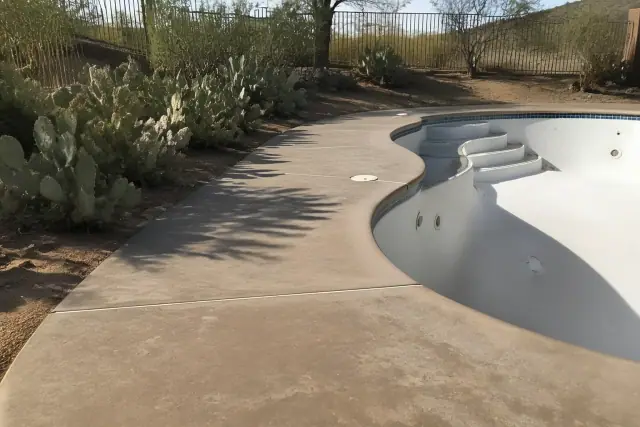 Pool deck coating project on a drained swimming pool surrounded by prickly pear cacti in Tucson, AZ.