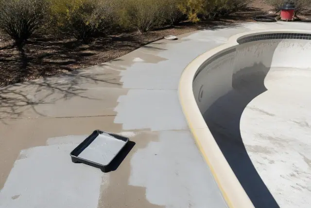 Concrete pool deck undergoing epoxy coating preparation at a residential site in Drexel Heights, AZ.