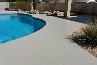 Textured anti-slip pool deck coating surrounding a water feature in a sunny Tucson, AZ backyard with desert landscaping.