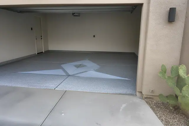 Empty two-car garage with a decorative flake finish floor and prickly pear cacti visible outside in Tucson, AZ.