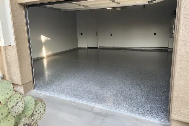 Empty residential garage in Tucson, AZ with freshly applied high-gloss polyaspartic floor coating and prickly pear cactus.