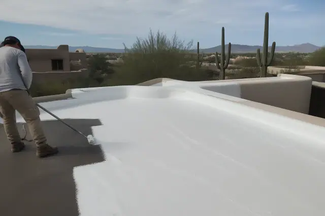 Freshly applied white acrylic elastomeric roof coating on a Tucson, AZ home with saguaro silhouettes in the background.