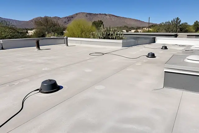 Moisture scanning sensors on a commercial flat membrane roof in Tucson, AZ, with desert cacti in the background.