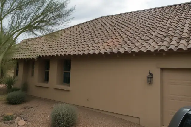 Newly installed clay roof tile interlocked with weathered tiles on a tan stucco home in Tucson, AZ.
