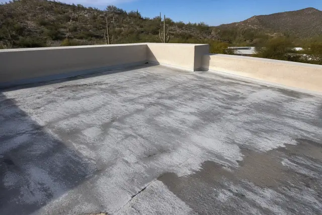 Close-up of chalking and hairline cracks in an acrylic roof topcoat with a Sonoran Desert view in Tucson, AZ.