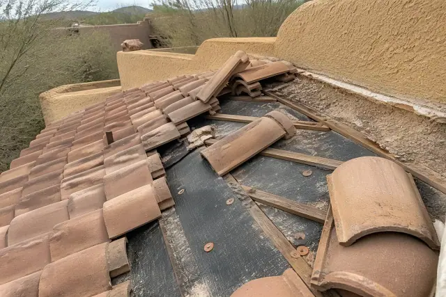 Roofer removing clay tiles to inspect the underlayment during a roof repair project in Tucson, AZ.