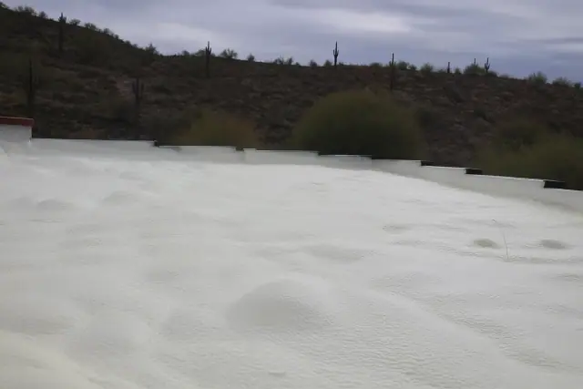 Polyurethane spray foam insulation on a flat roof with desert soil and saguaro cacti in the background in Tucson, AZ.