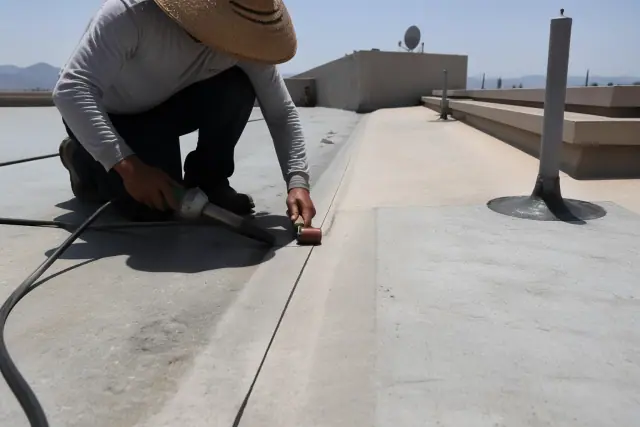 Technician performing commercial roof leak repair with heat-welded seams on a flat rooftop in Tucson, AZ.
