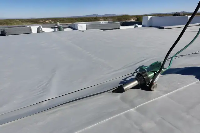 Professional using a heat-welding tool to seal seams on a flat commercial roof in Marana, AZ.