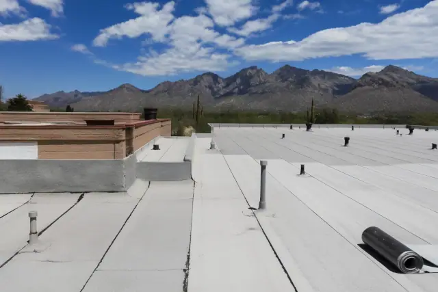 Professional applying heat-welded seams to a commercial roof in Oro Valley, AZ, with Catalina Mountains in the background.