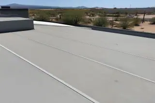 Heat-welded membrane roof seams on a commercial building in Tucson, AZ, with desert scrub in the background.