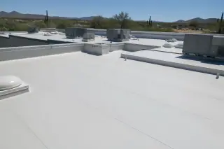 Finished heat-welded seams on a commercial flat roof with desert scenery in Tucson, AZ.