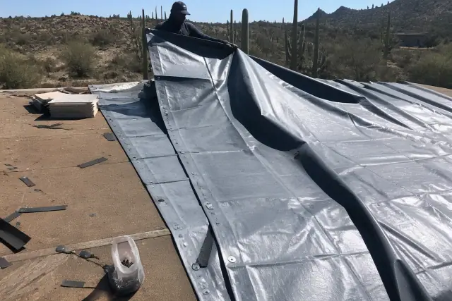 Heavy-duty tarp secured over a damaged roof section under the bright sun in Oro Valley, AZ.