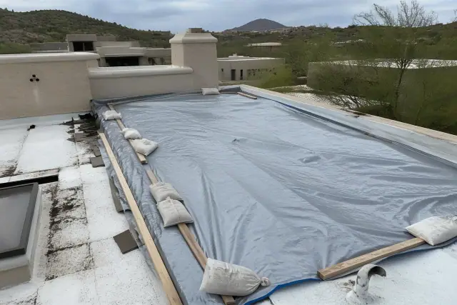 Reinforced tarp secured with sandbags and wood battens on a residential roof in Catalina Foothills, AZ.