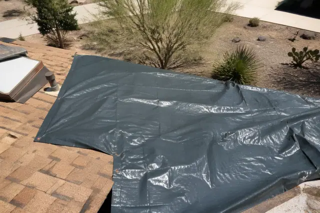 Heavy-duty tarp secured over damaged roof shingles during an emergency repair in Green Valley, AZ.