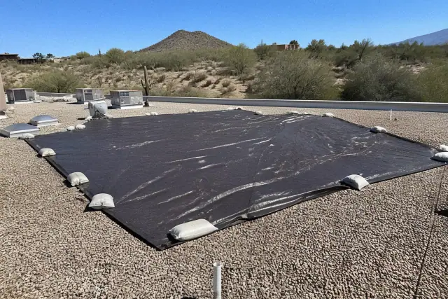 Heavy-duty reinforced tarp secured with sandbags over a damaged commercial roof section in Tucson, AZ.