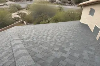 Finished shingle roof repair on a stucco home with desert vegetation in Tucson, AZ.
