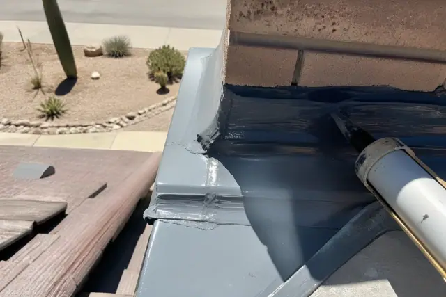 Contractor applying sealant to chimney flashing for roof repair in Tucson, AZ.